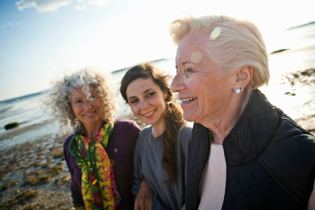 A diverse group of three women standing on a beach.