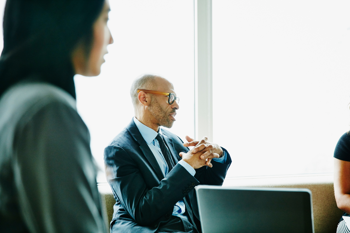 Mature businessman discussing project with colleague during meeting in office